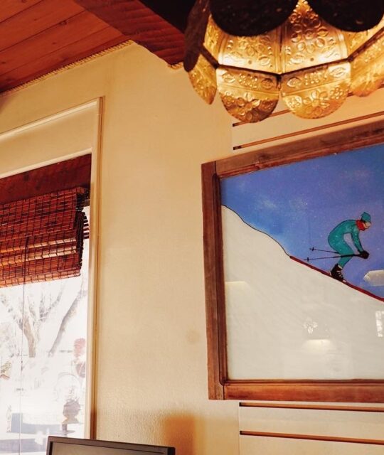 Entrance to El Pueblo Lodge reception with painting of skier and "Welcome to Taos" lamp.
