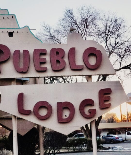 El Pueblo Lodge's iconic sign at sunset.