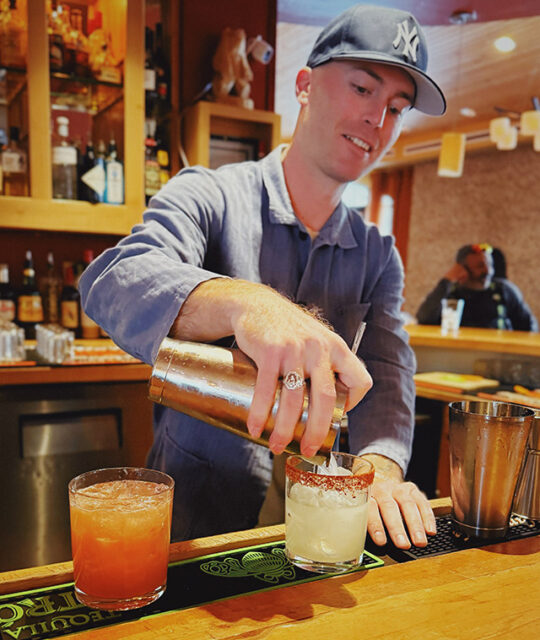 Smiling bartender mixing two drinks