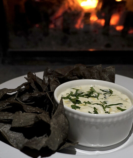 Blue corn chips and dip in front of the fireplace