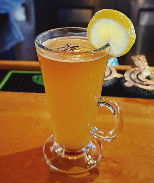 Boozy Hot Cider with lemon wedge at the bar