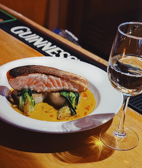 Scottish Salmon with Sticky Rice Cake, Oyster Bok Choy, Vietnamese Yellow Curry, and glass of wine