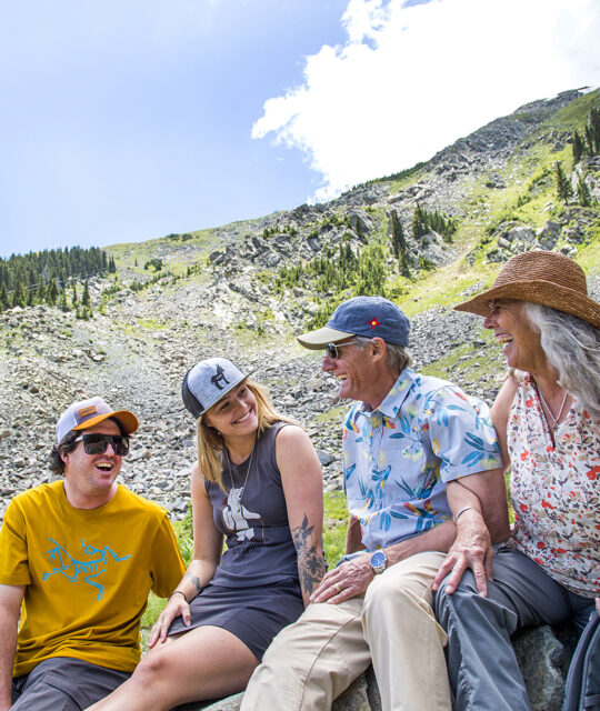 Summer and winter gear rental - A group of hikers take a break in front of a scree field