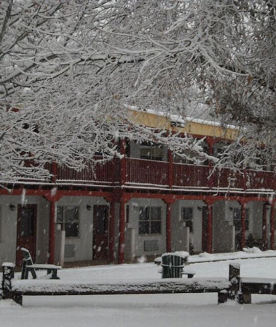 Snowy exterior of El Pueblo Lodge in winter.