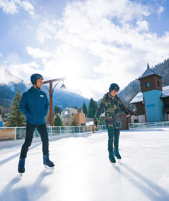 Couple ice skating at the Eis Haus ice skating rink in Taos Ski Valley.