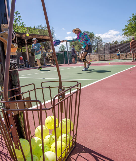 Pickleballs in basket and players at Quail Ridge Taos Tennis