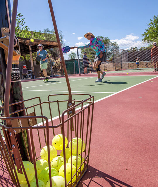 Pickleballs in basket and players at Quail Ridge Taos Tennis