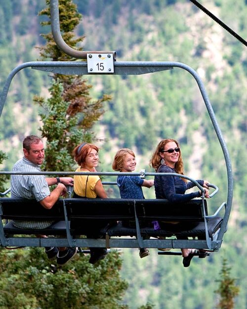 Family riding a ski chairlift in the summer