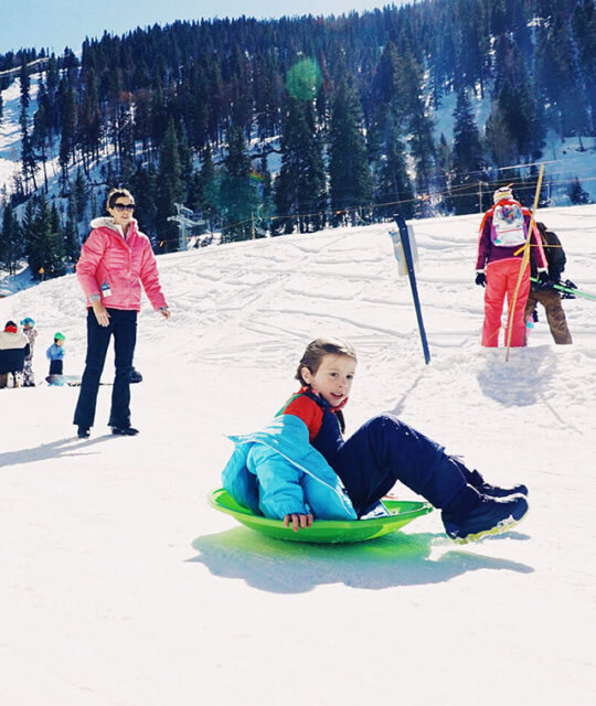 Girl sledding on a green saucer.