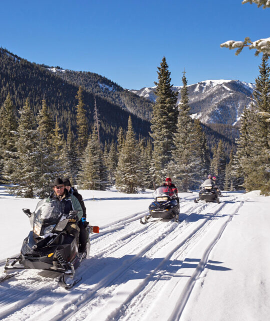 snowmobile tour group crossing a meadow