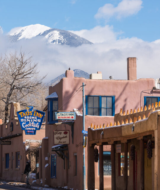 The Historic Taos Inn adobe building exterior with Taos Mountain in the background