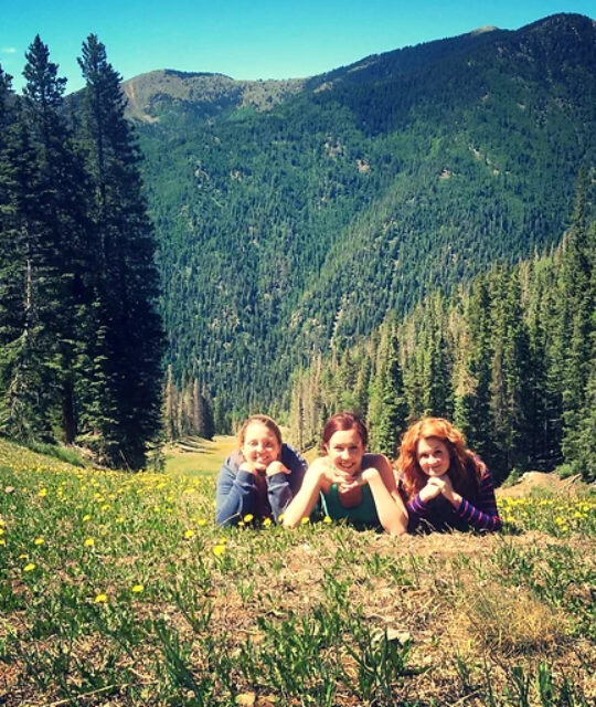 Three young women laying on a mountain side