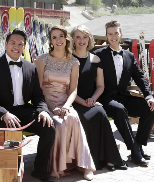 Young opera students in formal dress sitting on a bench made of skis