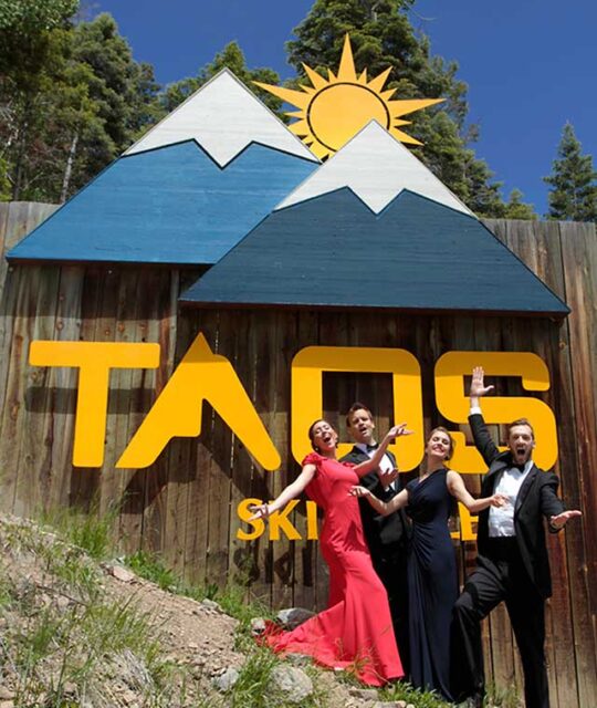 Taos Opera Institute singers in front of the Taos resort sign.