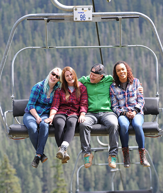 A group of friends high in the air on a summer chairlift