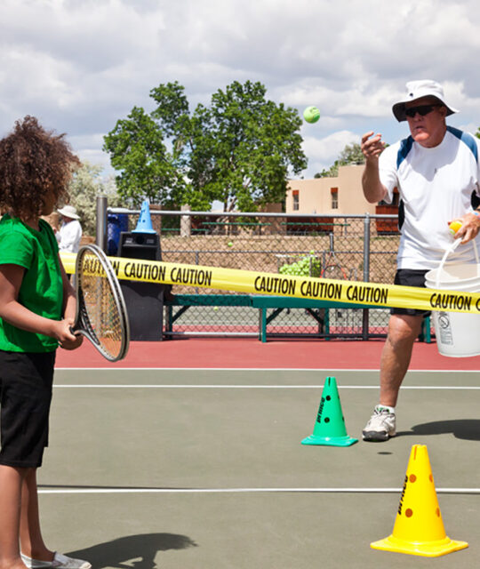Tennis instructor with young child