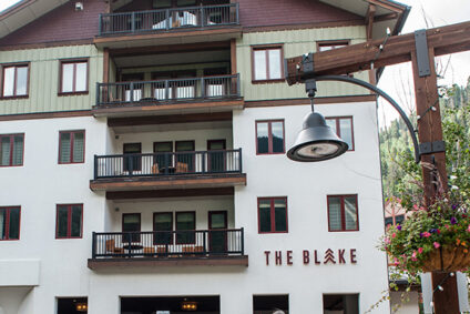 Family with suitcases walking toward The Blake in Taos Ski Valley