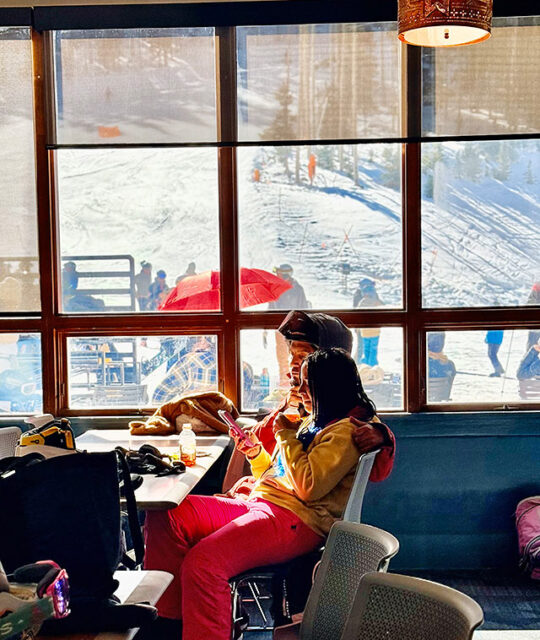 Skiers enjoying a sunny view while having lunch.