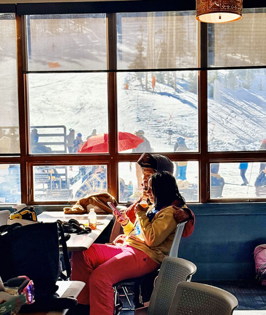 Skiers enjoying a sunny view while having lunch.