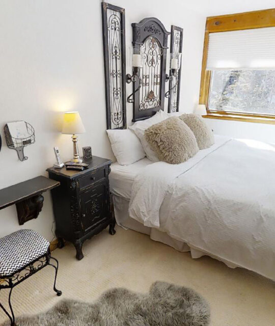 A bright bedroom with white bedding and black accent table