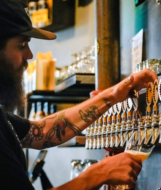 Bartender drafting a pint of beer at Taos Mesa Brewing Tap Room.