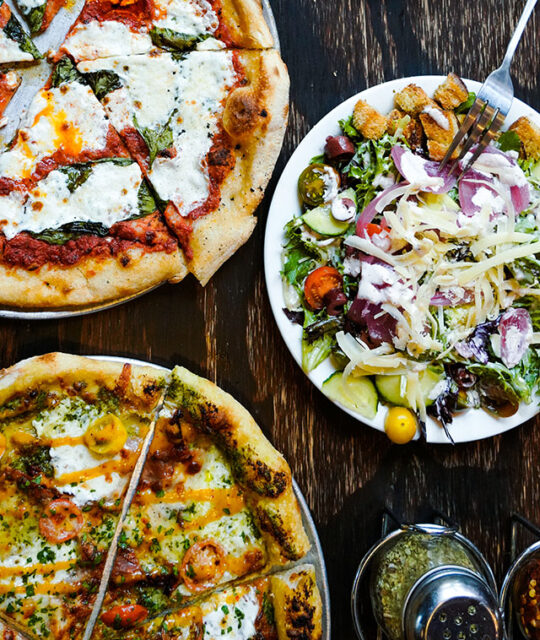 Overhead shot of pizzas and salad from Taos Mesa Brewing Tap Room in Taos, NM.