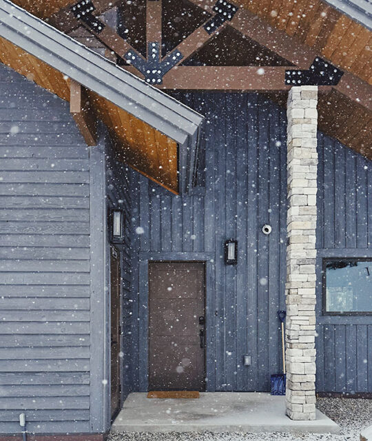 Entrance to ski chalet M Vacation Properties with snow falling