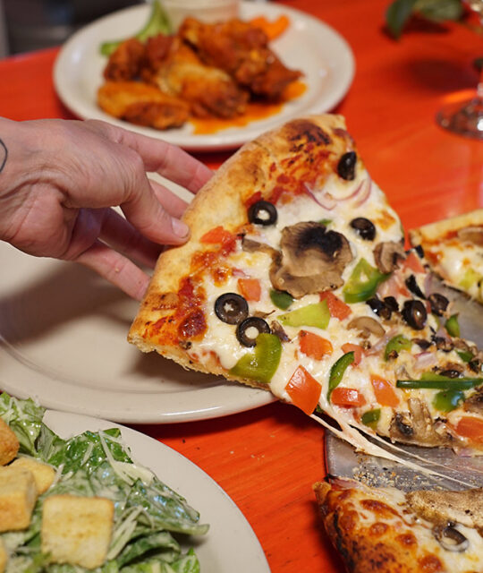 Pizza slice with salad and wings.