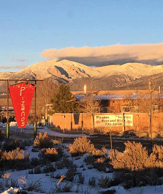 Pizaños pizza and pasta sign and winter sunset on Taos mountains