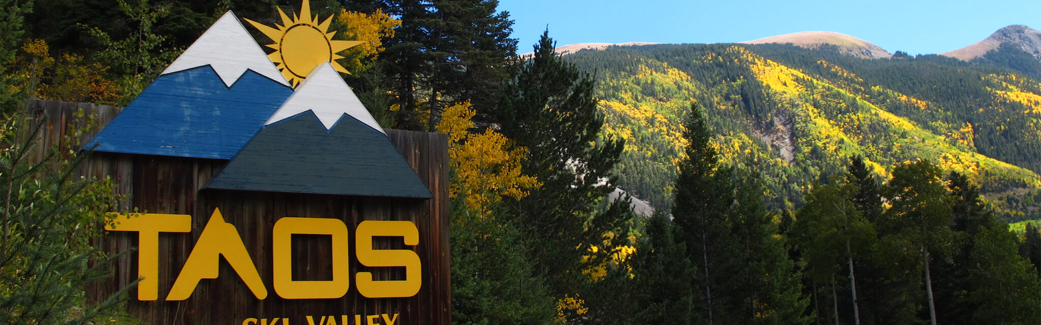 Taos Ski Valley welcome sign in the fall with colorful aspens.