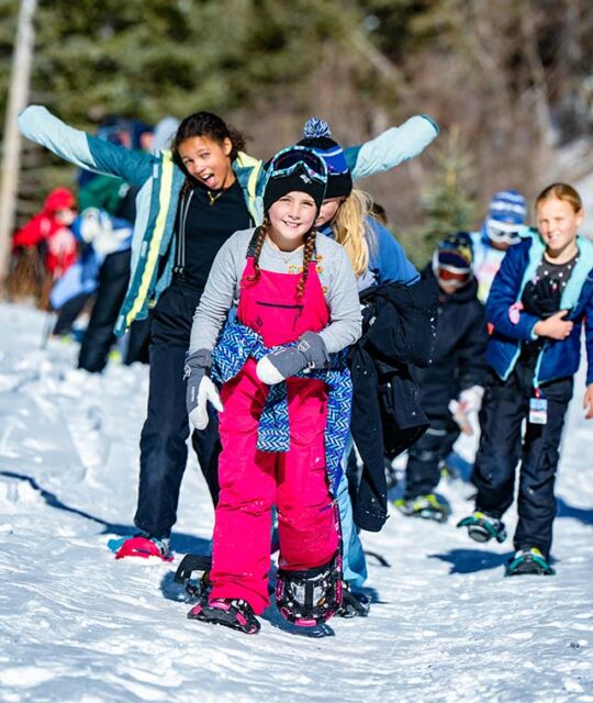 A group of kids having fun snowshoeing.