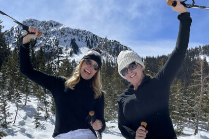 Two women snowshoers raising their poles