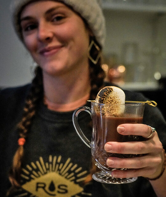 Cute bartender serving hot coco at The Lounge by Rolling Still Distillery