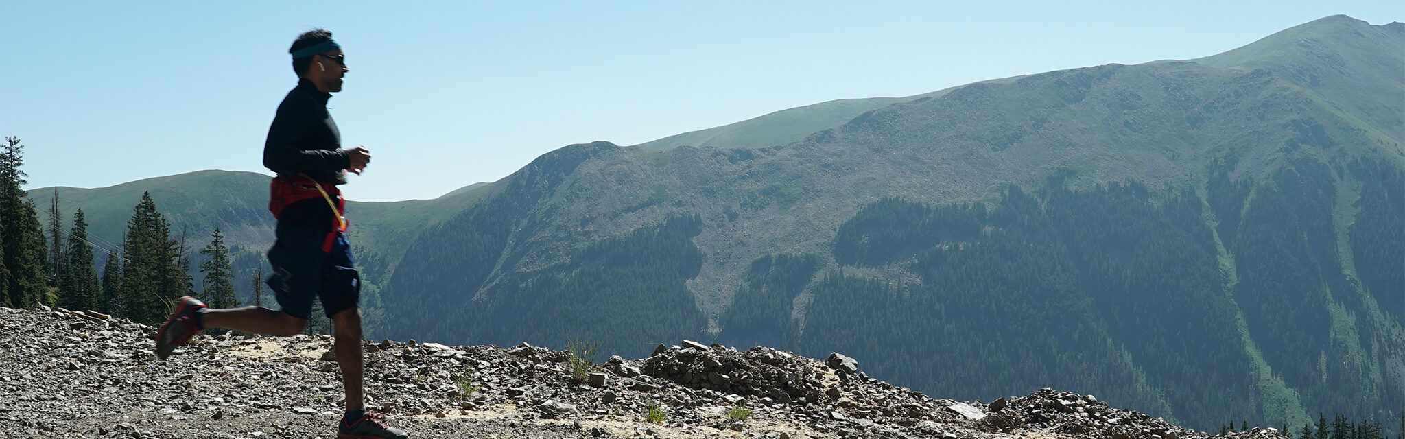 A lone runner in front of a mountain backdrop in a challenging 10k trail run