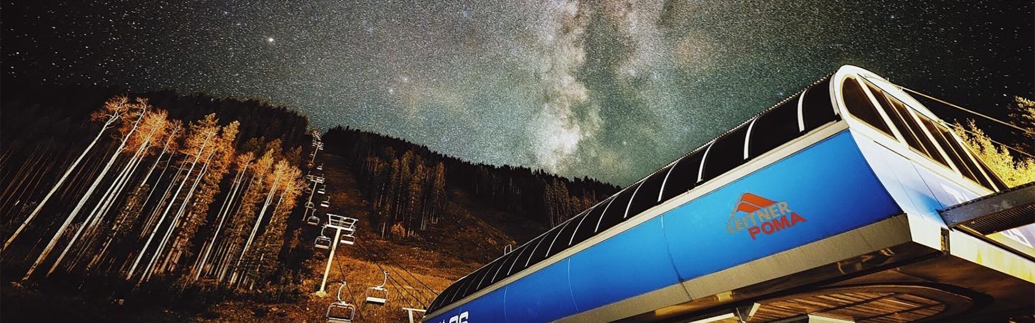 The milky way shines brightly over a ski lift house.