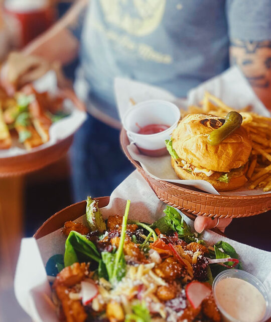 Server with burger and fries and salad.