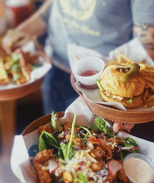 Server with burger and fries and salad.