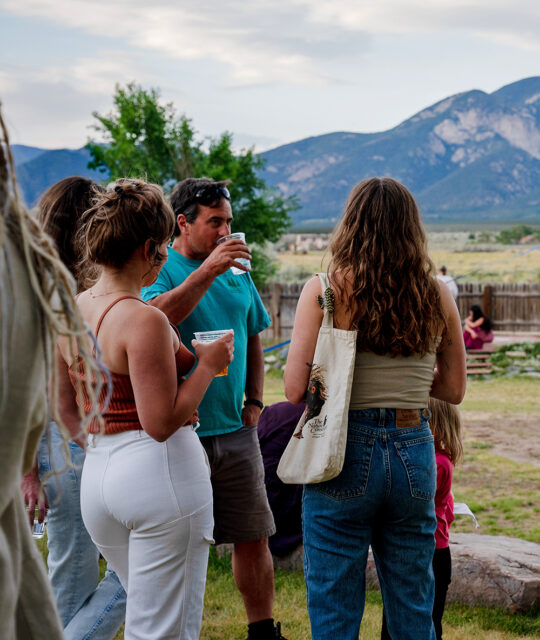Group enjoying drinks outdoors in the summer and mountain backdrop.