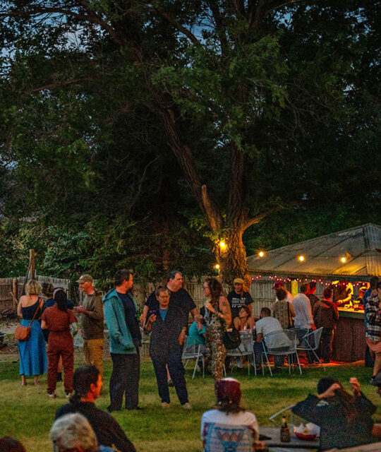 People enjoying drinks in the evening at a tiki hut.