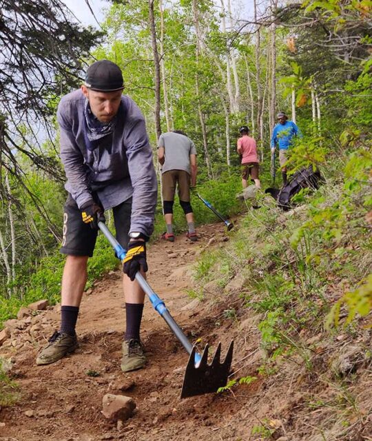 Mountain bikers doing trail work with McLeods.