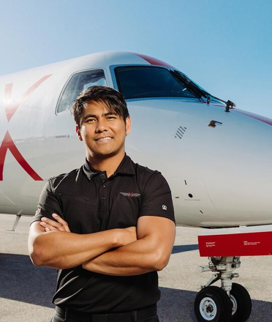 JSX airline pilot in front of plane.