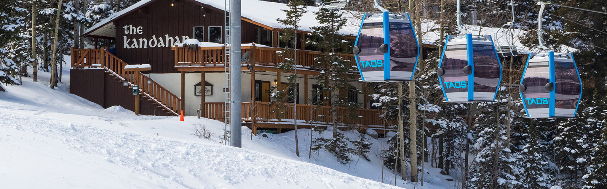 The TAOS gondola passes in front of a snow Kandahar Condos building.