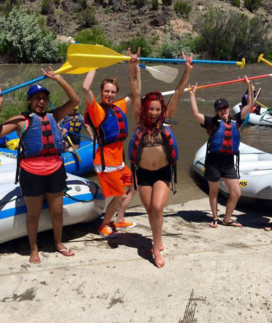 Rafting customers with paddles up and having fun.