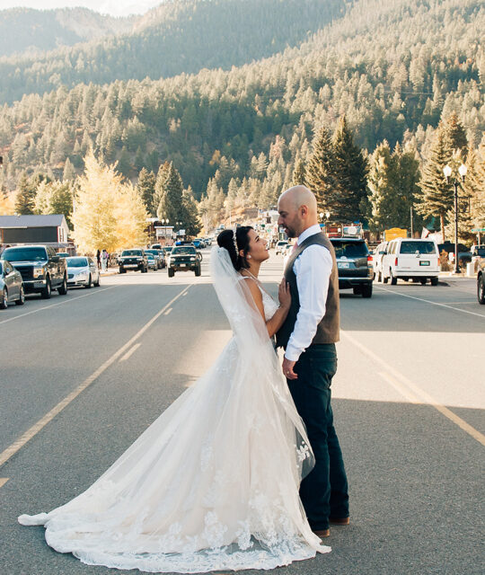 Bride and groom standing in middle of a street in a mountain town.