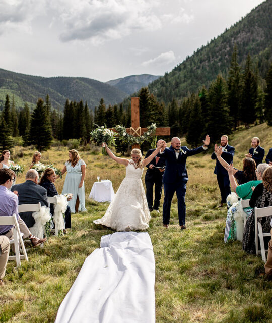A summer outdoor mountain wedding ceremony with a cross backdrop planned by KWK Events.