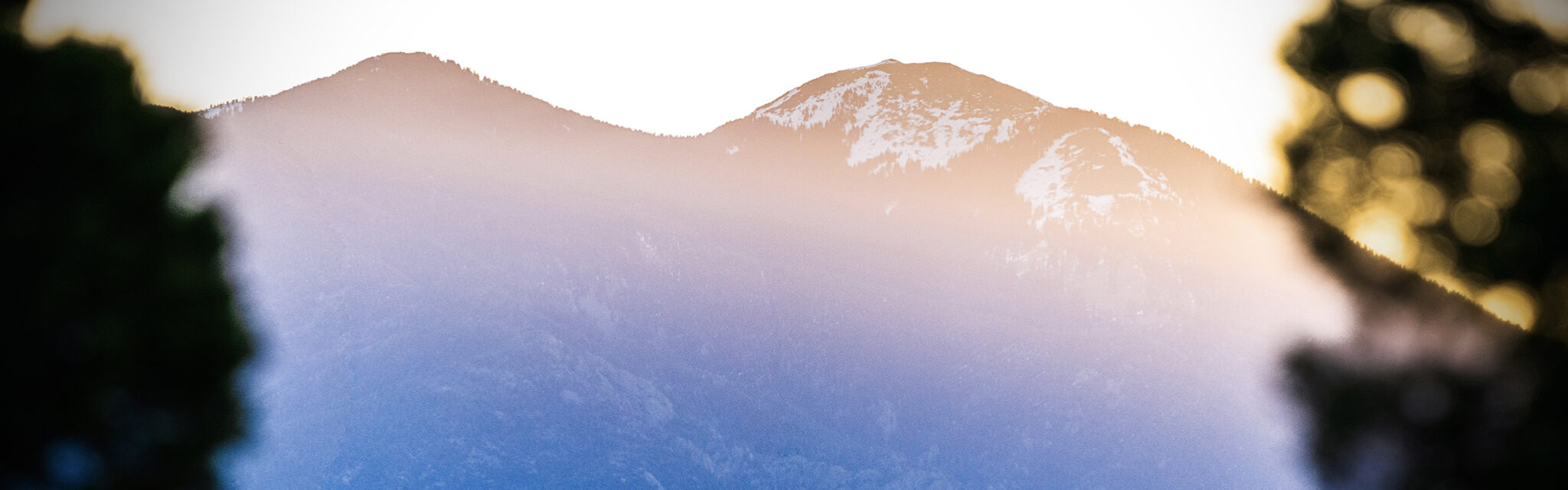 The contrast of blue and orange reflect on a snow capped mountain at sunrise.