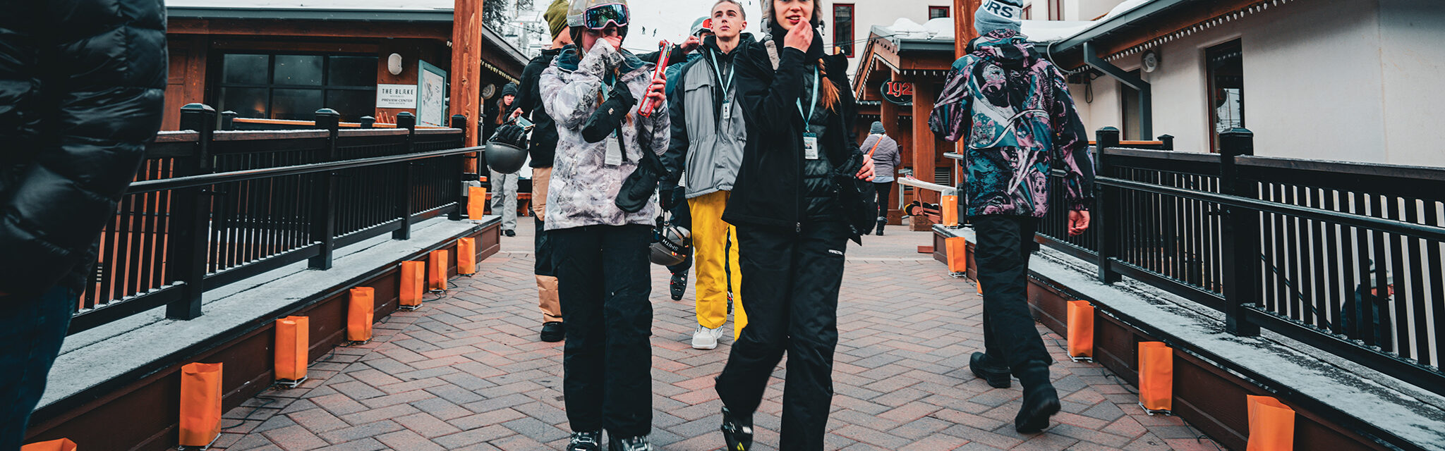 A group of young women walk down a path dressed in ski boots and snow gear.