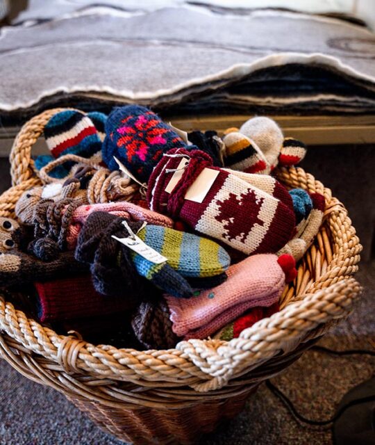 Basket of colorful handmade winter mittens for sale.