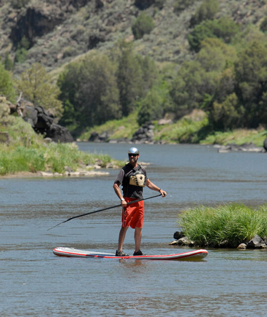 Man SUP stand up paddleboarding on the Rio Grande near Taos