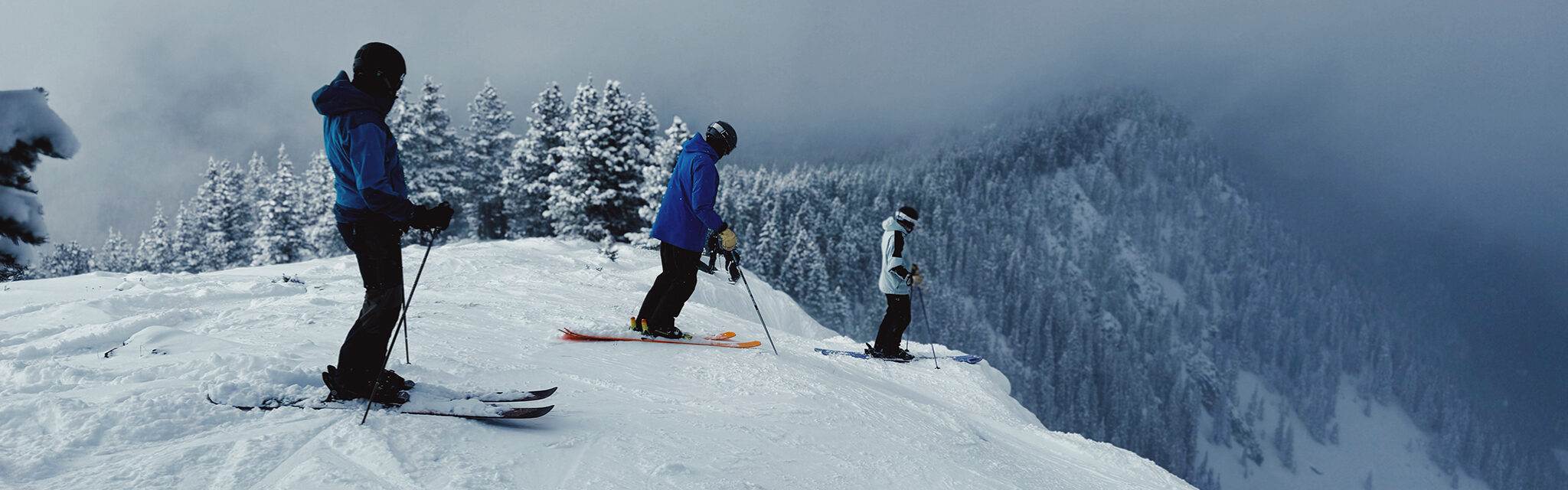 Skiers prepare for a run that looks like a sheer drop off.